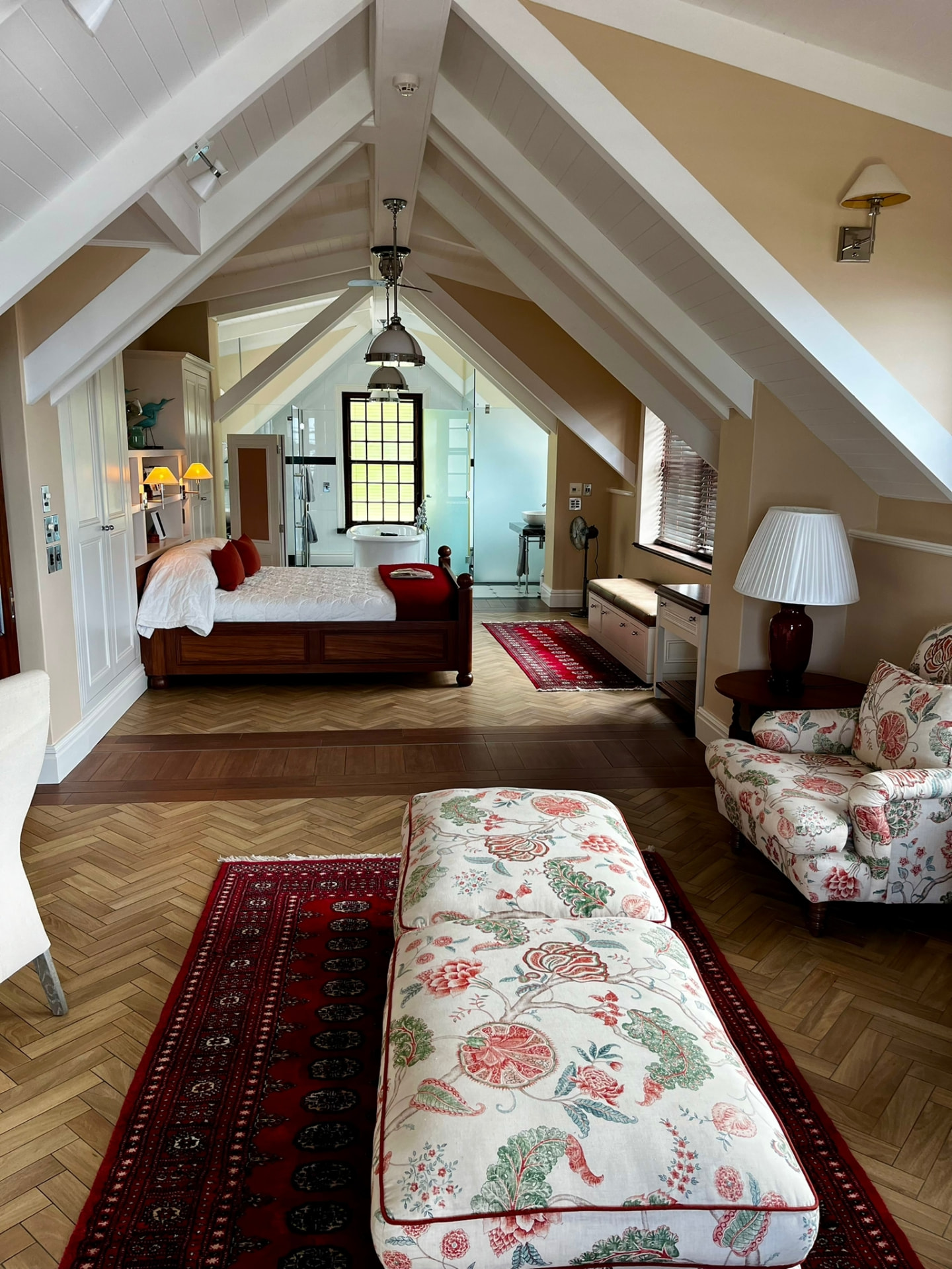 Attic bedroom with white beams, antique furniture and patterned textiles