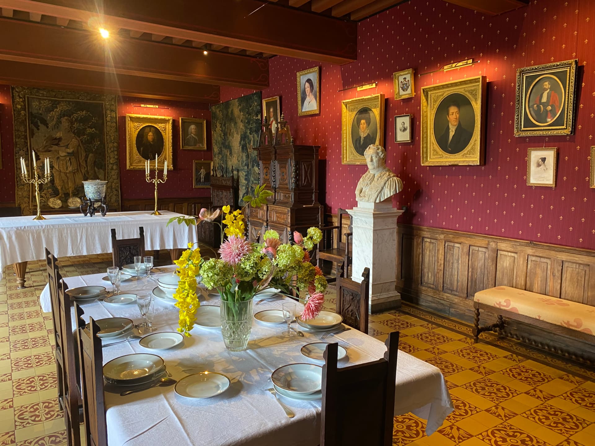 Historic dining room with portraits, sculpture and a laid table