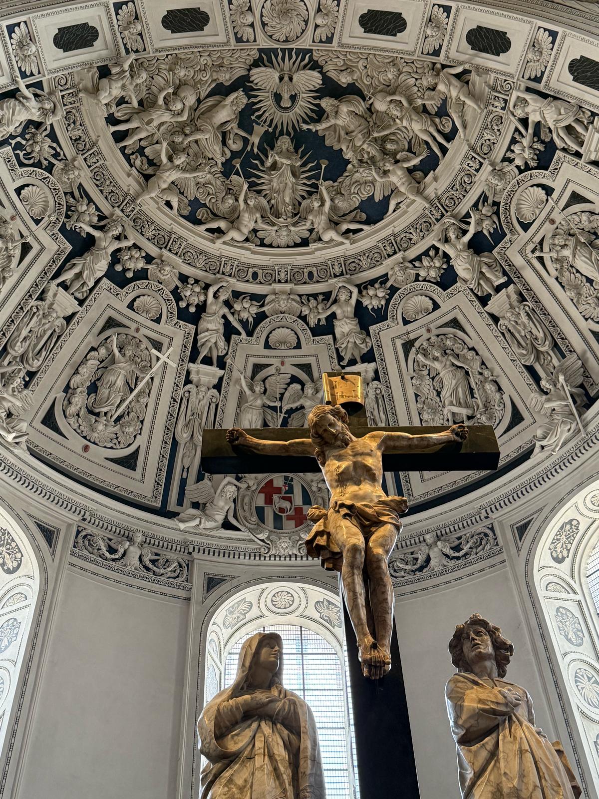 Sculptural crucifix beneath an ornate historic chapel ceiling